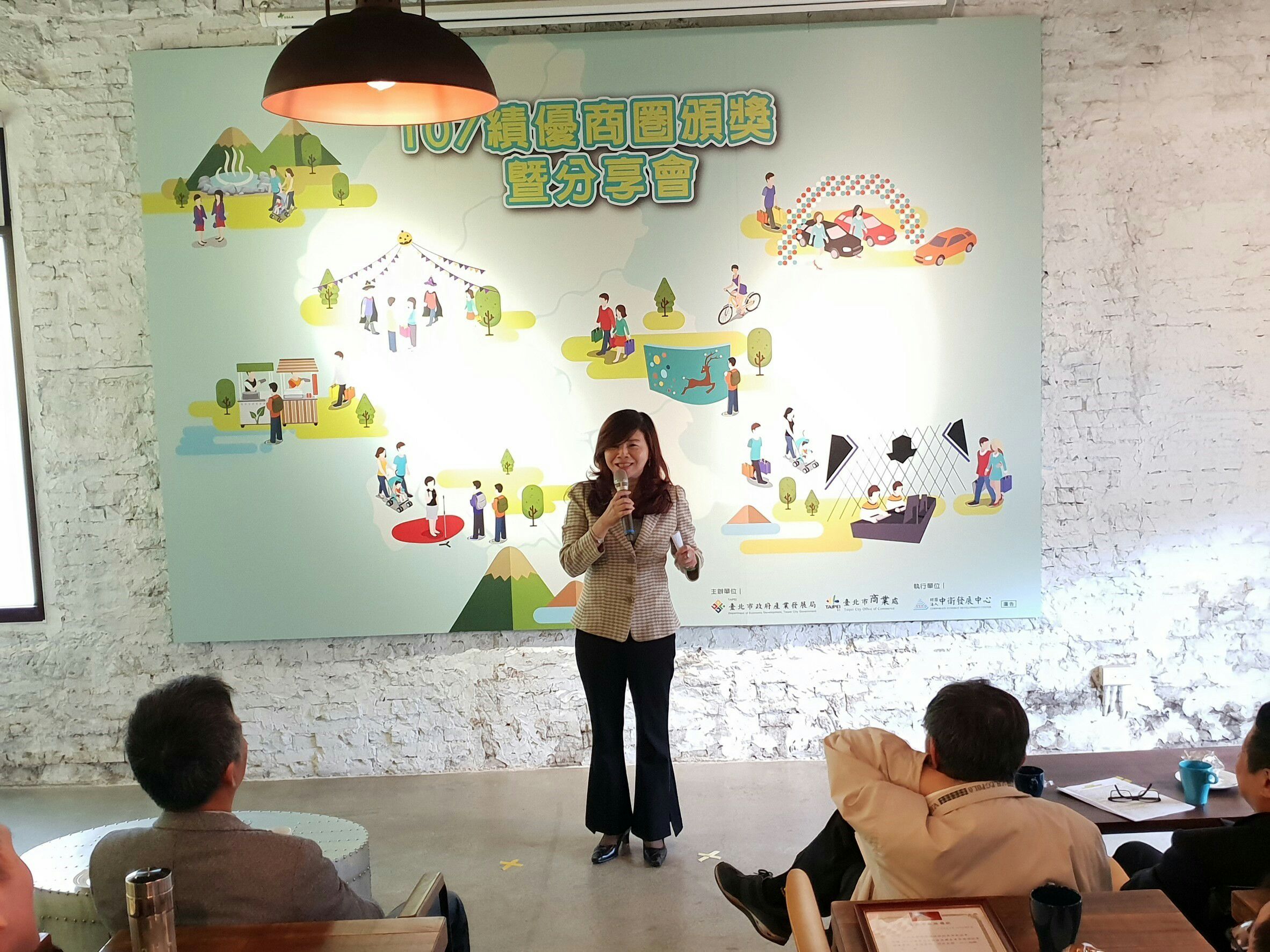 Chairperson Chou Shui-Mei sharing commercial district experience on stage.